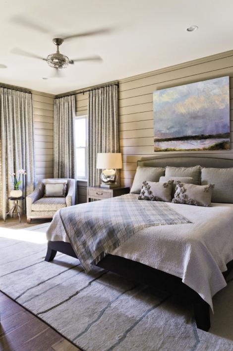 Mellow Out: Poplar wood paneling wraps a master bedroom (one of two in the house). The Tufenkian rug is from Tibet and the landscape painting is from Rebekah Jacob Gallery.