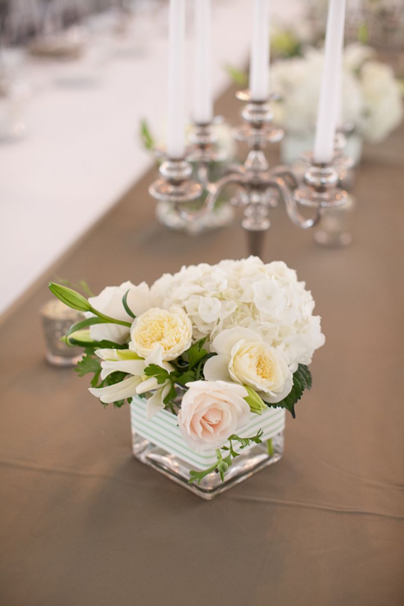 SET THE TABLE: Placed between vases brimming with pale posies, candelabras cast a glow over tabletops as guests dined.