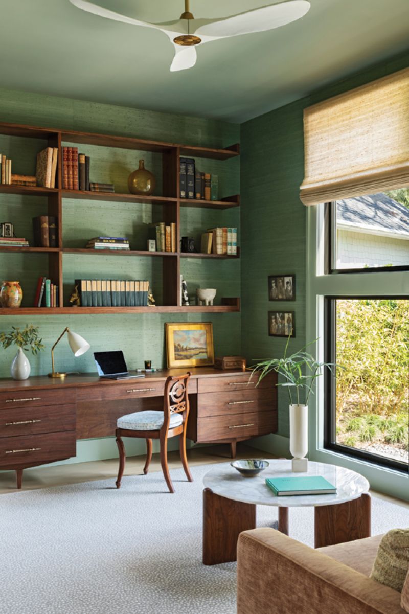 A Room of One’s Own: A green jute grass-cloth wall covering envelopes the wife’s office, creating a calming, inspiring space. A custom walnut bookcase houses her antique book collection, and the round white quartz coffee table from CB2 balances the space.