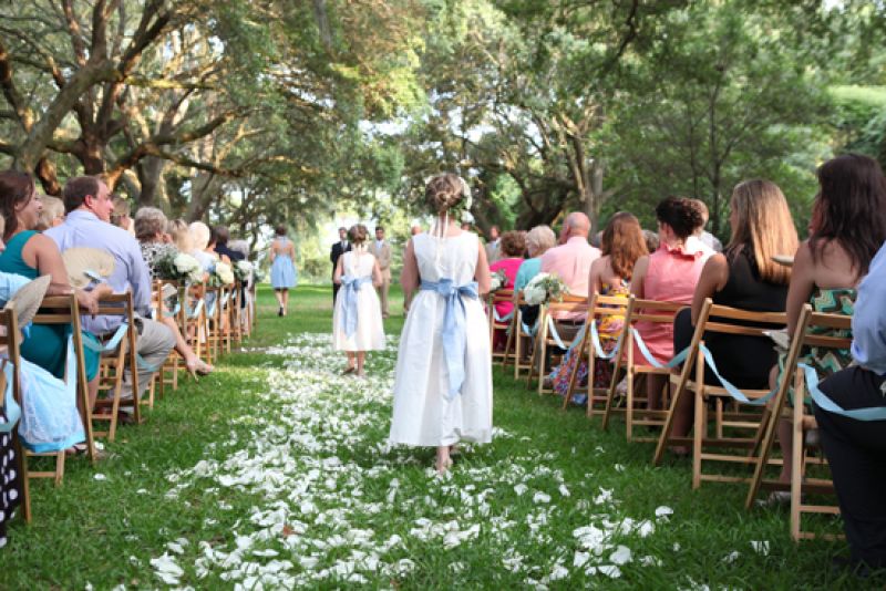 CRISP COORDINATION: The groomsmen’s ties, the flower girl sashes, and the ribbon that was draped down the sides of the aisle each matched the hue of the bridesmaids’ open-back dresses Bella Bridesmaid of Charleston.
