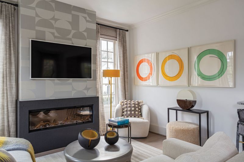 In the family room, Brown was inspired by the Robert Mangold triptych. From the geometric Holly Hunt “Regents Street” wallpaper—a nod to the ’60s Op Art movement—to the round Rose Tarlow lamp, the room has an exciting abstract feel. Pops of color in the Romo pillows and the floor lamp tie it all together.