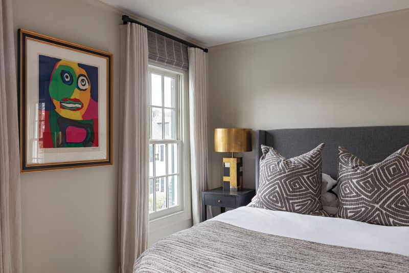 The guest bedroom features vintage brass lamps and a colorful Karel Appel lithograph.