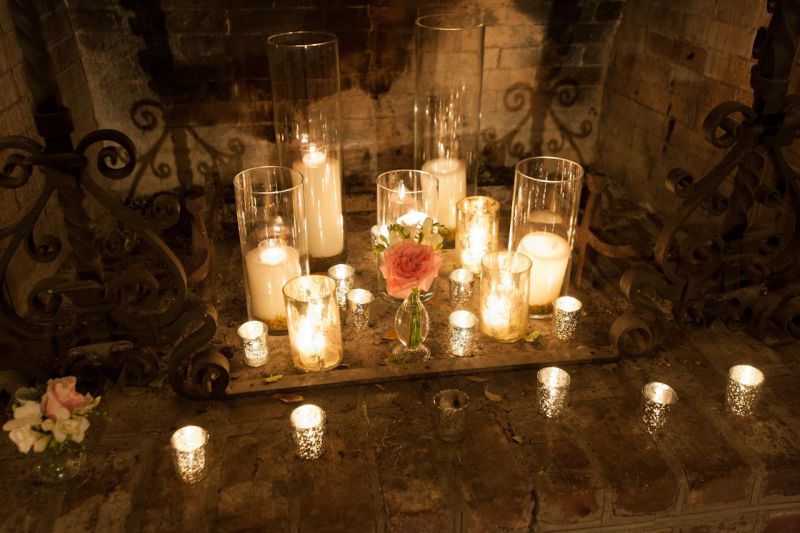 STATE OF GRACE: Mercury glass votive candles, cylinder glass candleholders, and petite flower vases brought elegance to the rural fireplace.