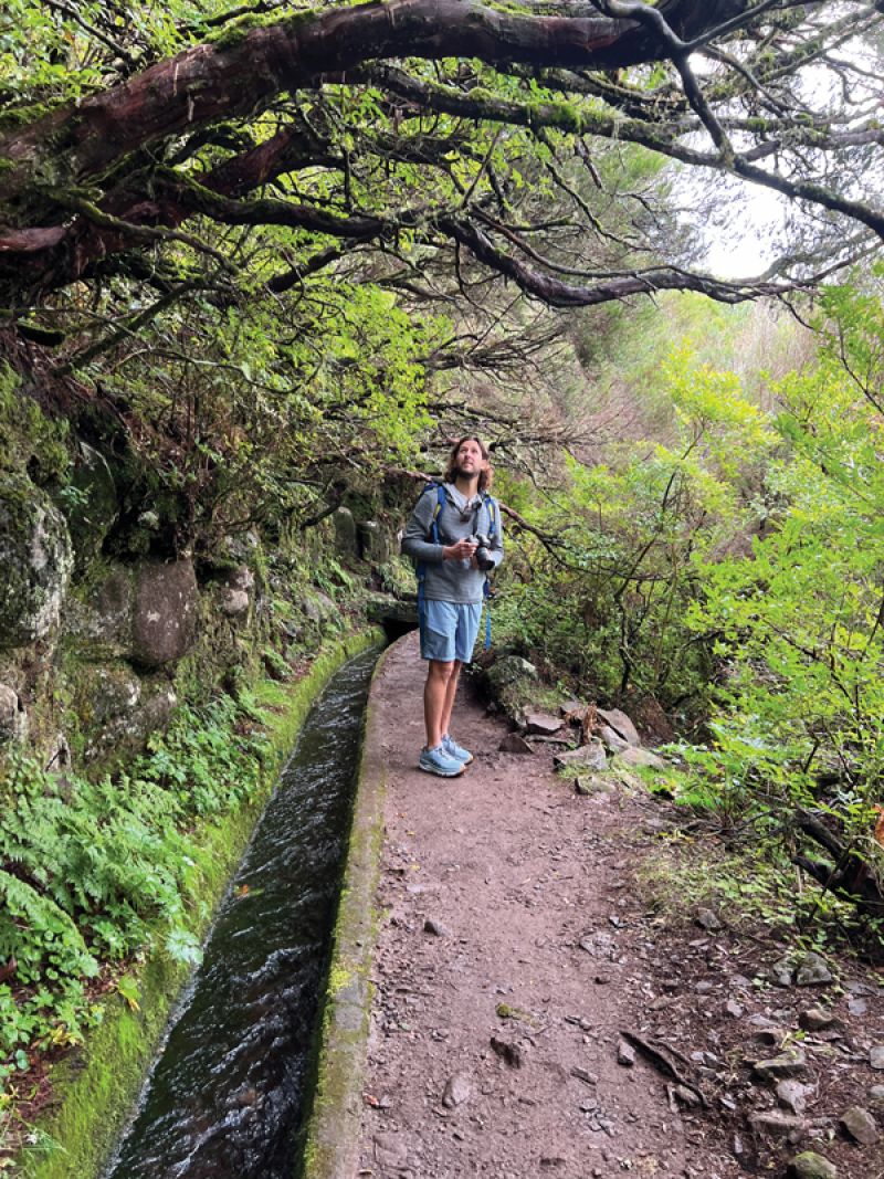 Stratton pauses to admire a bird while hiking along a levada—a canal used to divert water to farms below—in Madeira’s mountainous forests.