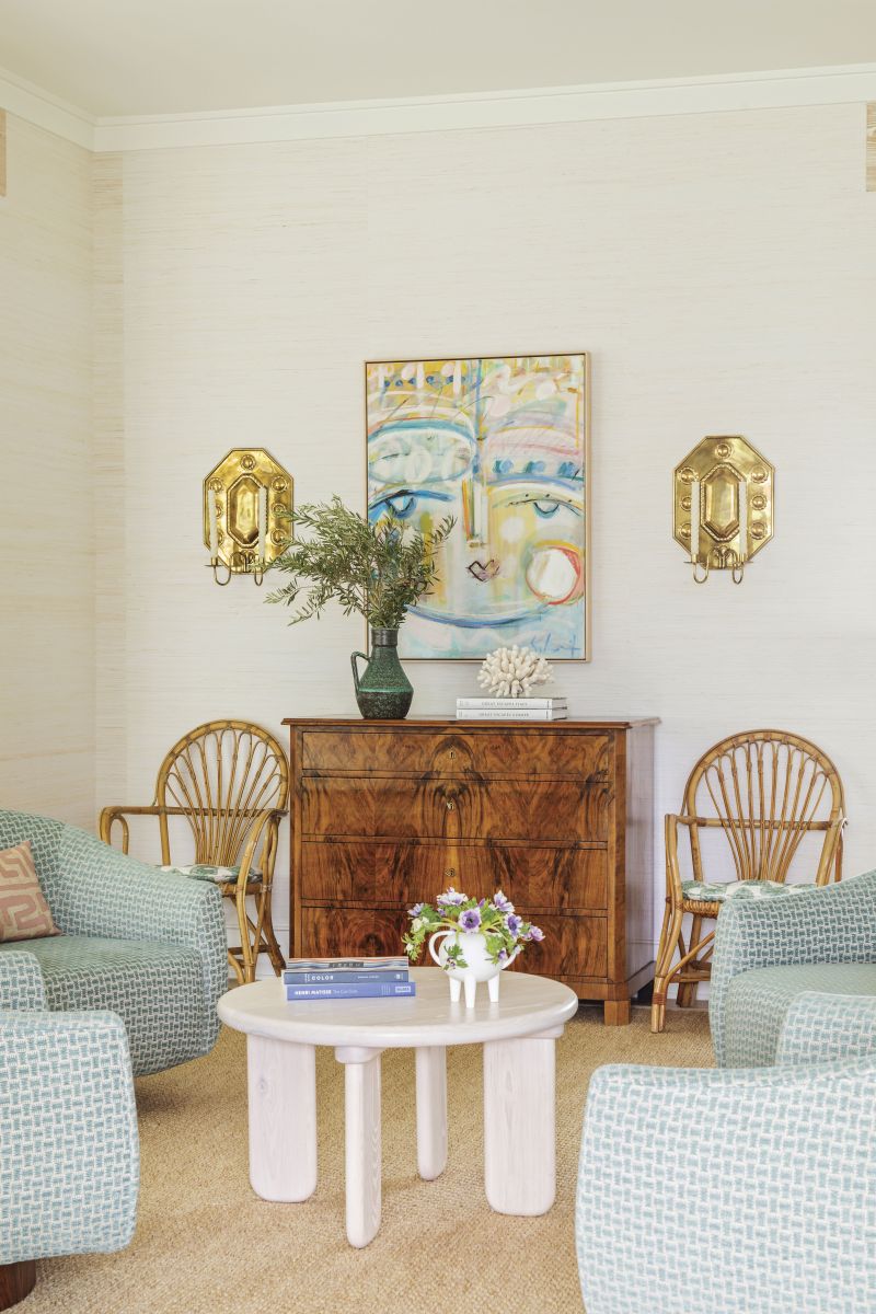 EYE CANDY: Calculated pops of vibrant color—such as in this Sally King Benedict painting hanging above the Biedermeier chest—and gleaming brass add intrigue to the home’s mostly muted palette.