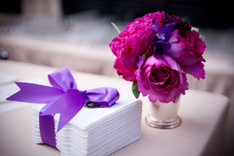 DRAMATIC DETAIL: Bright purple ribbon used to tie off a simple stack of napkins provided another burst of color that reinforced the wedding’s palette.