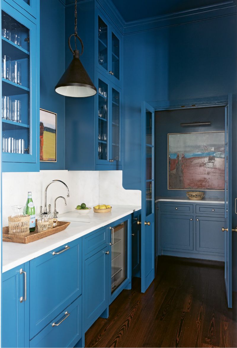 BRIGHT SPOT: Cabinets lacquered in Benjamin Moore “Blue Danube” pull the eye through the neutral kitchen into this daring butler’s pantry. Two Sandy Ostrau works from Meyer Vogl Gallery add to the dramatic, contemporary feel.