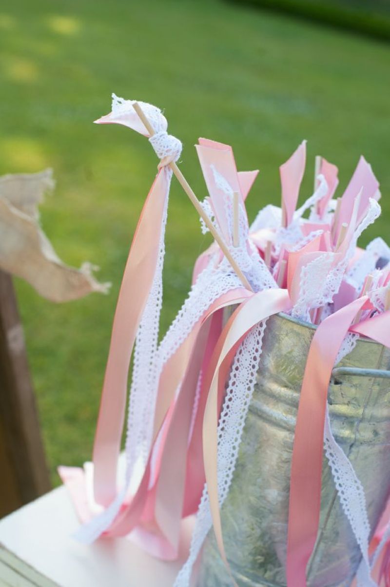 A WHIMSICAL TOUCH: Before taking their seats, guests picked up one of the bride’s handmade contributions—wishing wands made of pink and white ribbons to wave as the newlyweds walked together up the aisle.