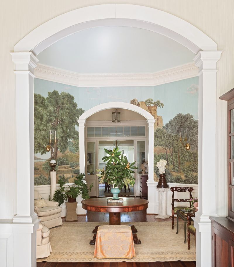 SCene Stealer: The 18-foot ceilings in an octagonal room at the center of this circa-1877 Summerville house rise to a dramatic skylight dome replete with an original plaster crown. The high rosette window brings the only natural light into the room, so designer Alaina Michelle Ralph created a “view” using a scenic Iksel wallpaper and lightened the room by extending the “sky” with Benjamin Moore’s “Woodlawn Blue” paint. The mural depicts an idyllic Italian countryside scene evoking the home’s Italianate architectural style.