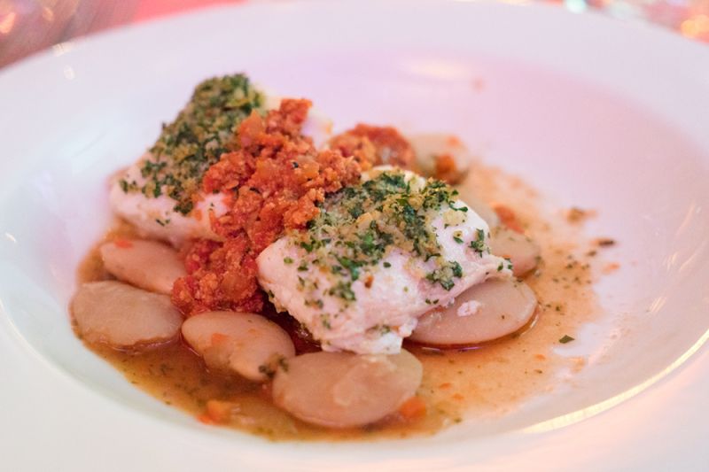 Olive oil-poached Alaskan halibut with an herb-lemon crust, romesco sauce, and gigante bean brodo