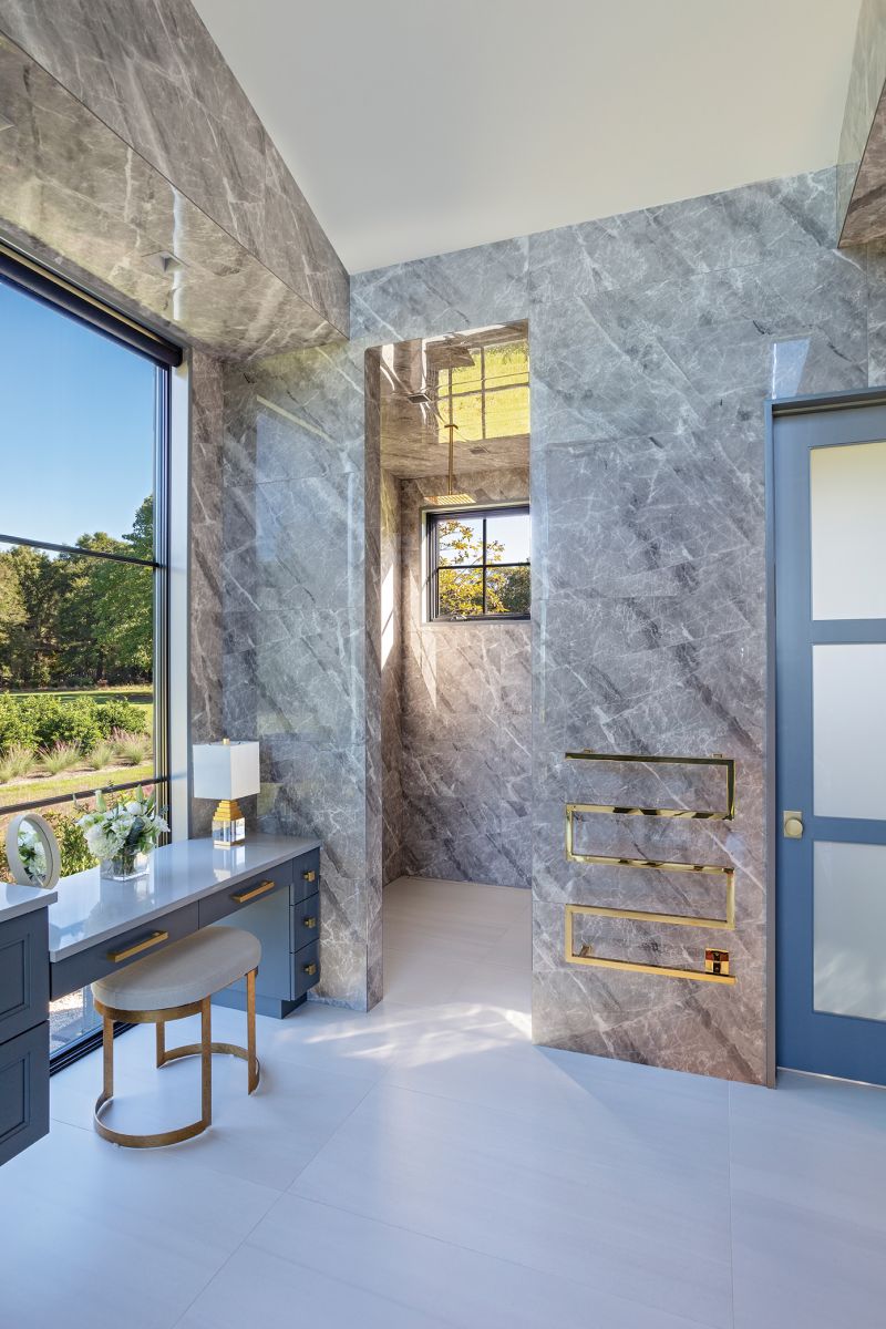 The walk-in shower—with a lateral drain so there’s no need for a door—boasts a modern brass towel heater.