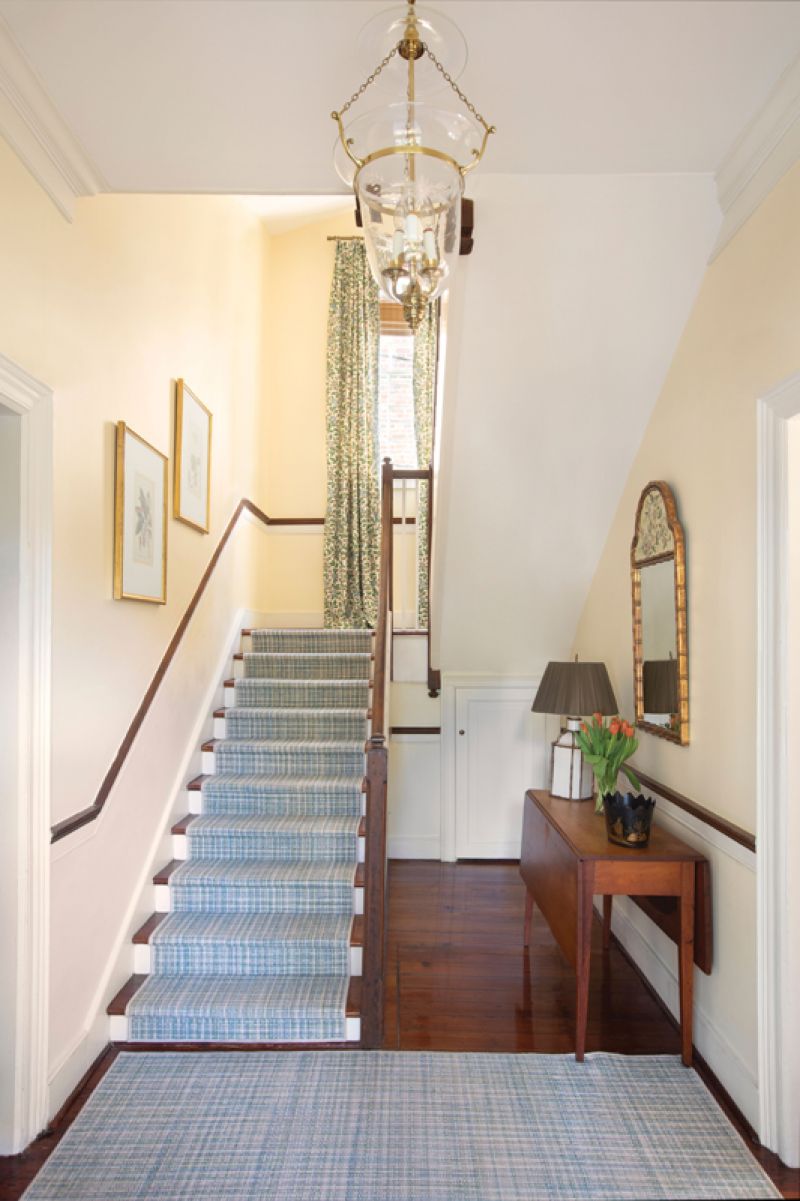 Caitlin added interest in the entry hall with a blue rug and stair runner from Designer Carpets on John’s Island and floral drapes. Benjamin Moore’s soft “Windham Cream” paint highlights the original wood floor and antique console table.