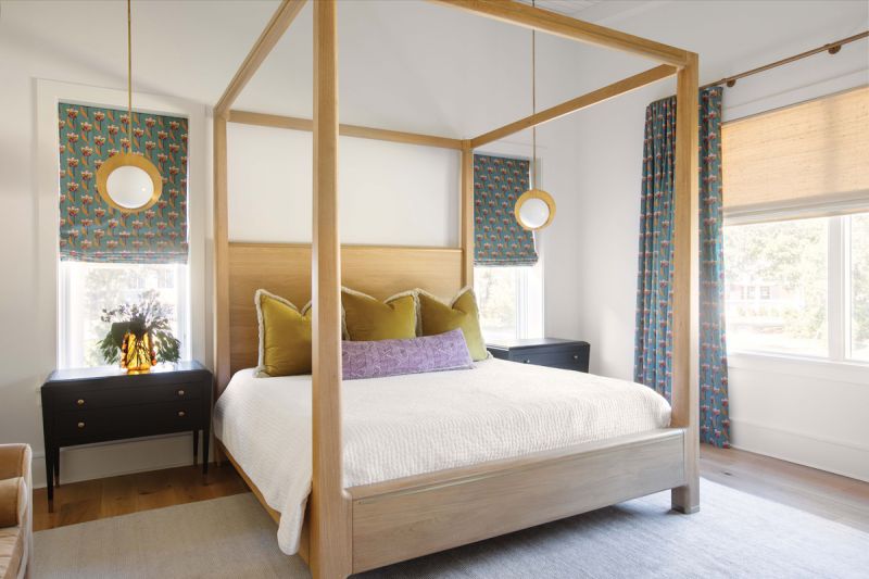 The primary bedroom suite features a white oak bed with brass inlay and brass pendant lights that pick up on the flecks of gold in the deep blue shades.