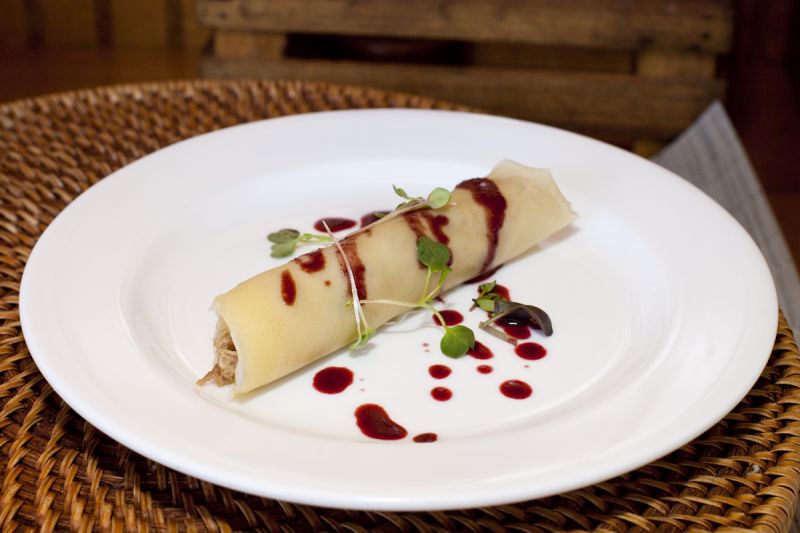 A close-up on Duck Confit Crespelle with a blackberry balsamic reduction