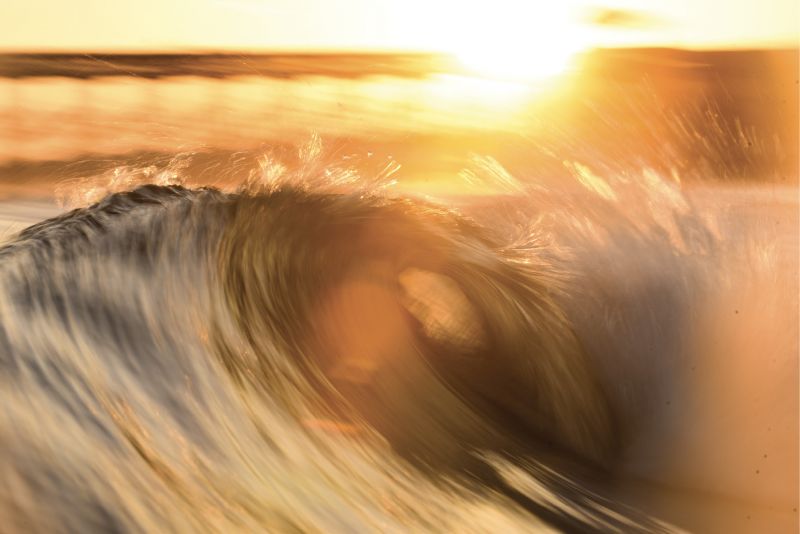 A setting sun and a slower shutter speed capture the movement of the waves.