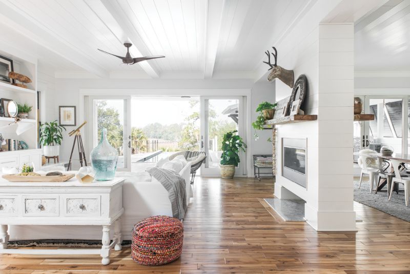 White Out: Melissa describes her home style as clean-lined and coastal. All-white built-ins and furnishings in the living room feel fresh, while acacia wood floors warm the neutral palette. In the otherwise open layout, a wraparound fireplace helps to create distinct zones for lounging and eating.