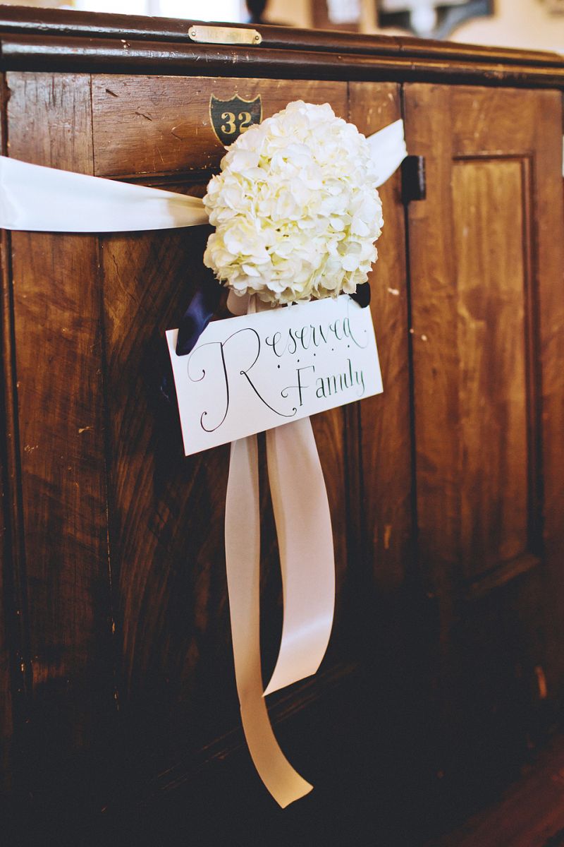 FAMILY FIRST: A large white hydrangea tied with ribbon reserved the front pew for members of the couple’s family.