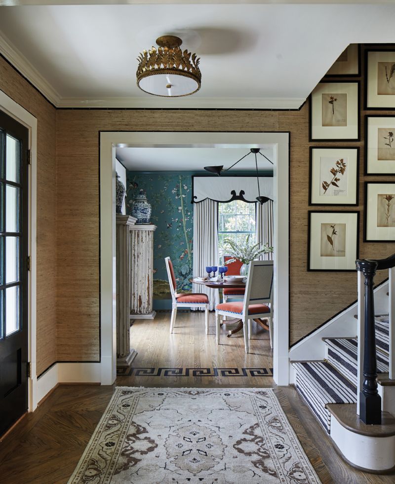 A grasscloth-swathed foyer—featuring a black grosgrain ribbon trim—separates the rich spaces.