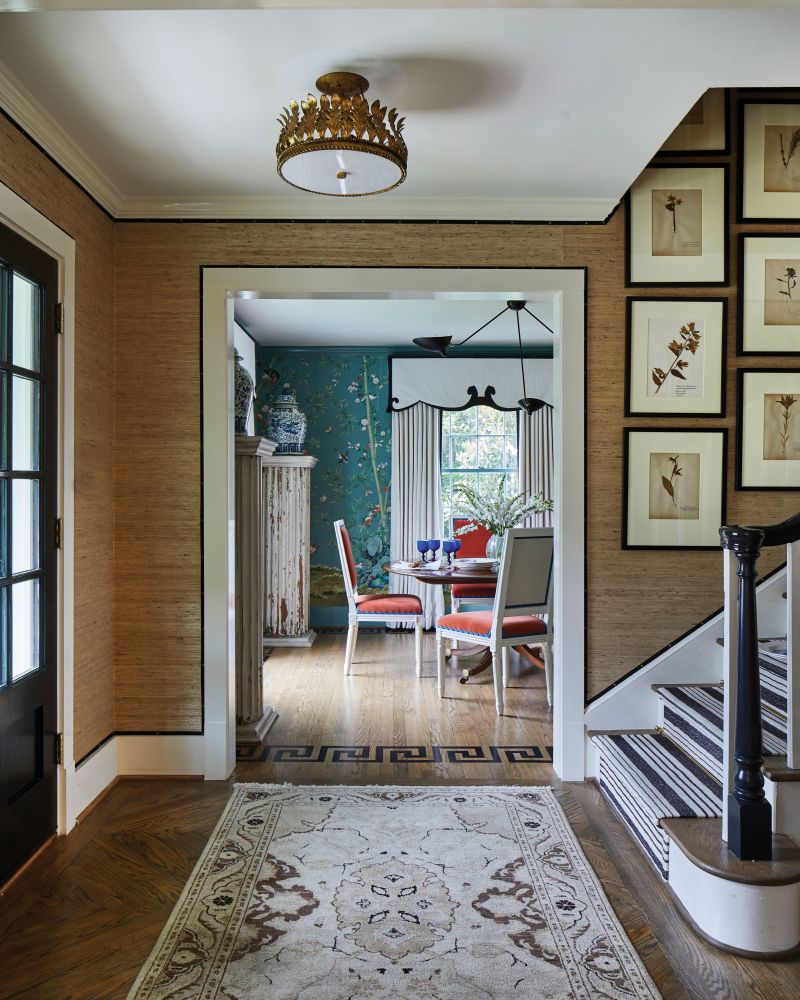 In the foyer, grasscloth-covered walls with black grosgrain ribbon trim aptly frame the whimsy of the adjacent dining room.