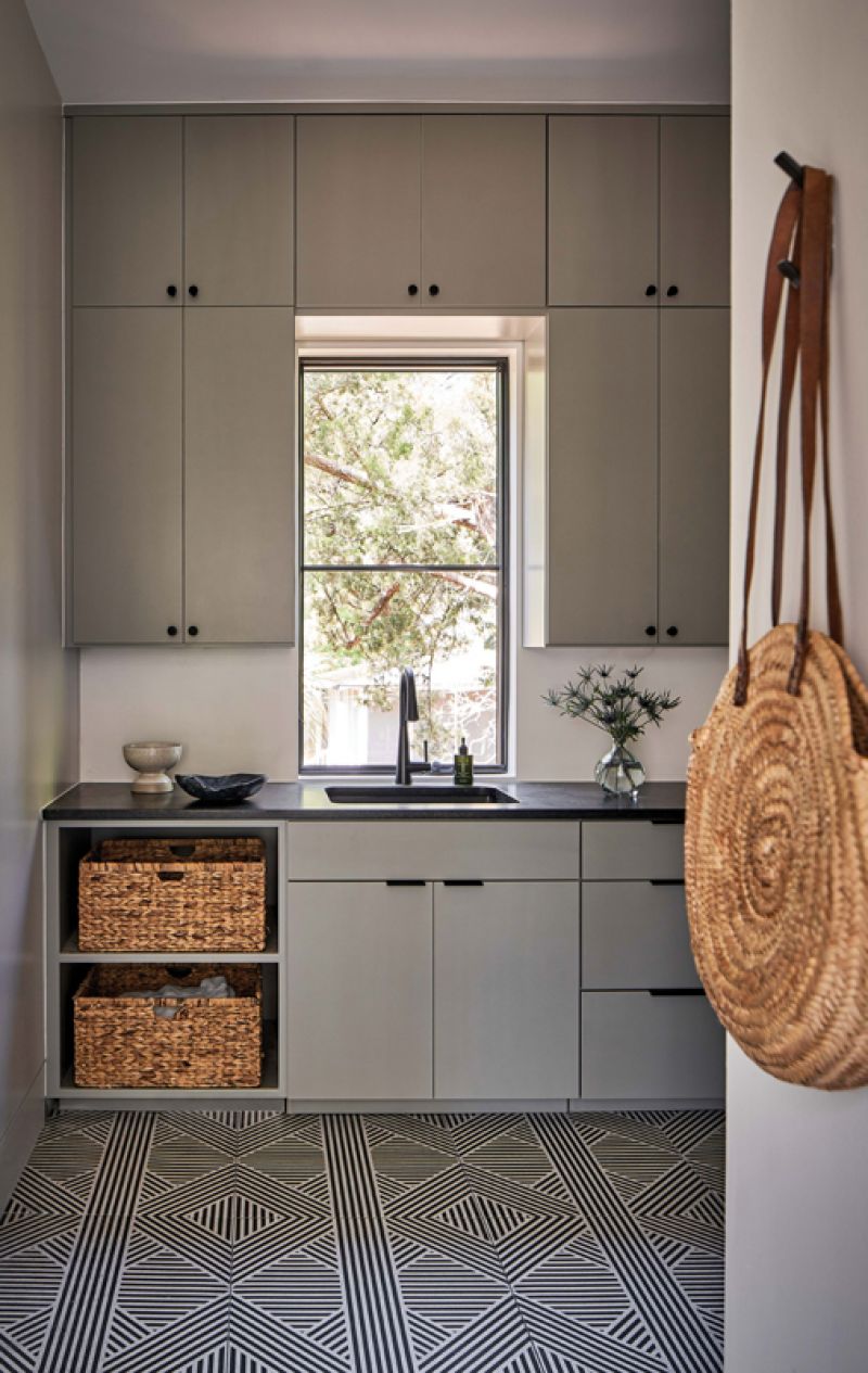 Cool grey and green tones in the laundry room are warmed up by natural wicker baskets.