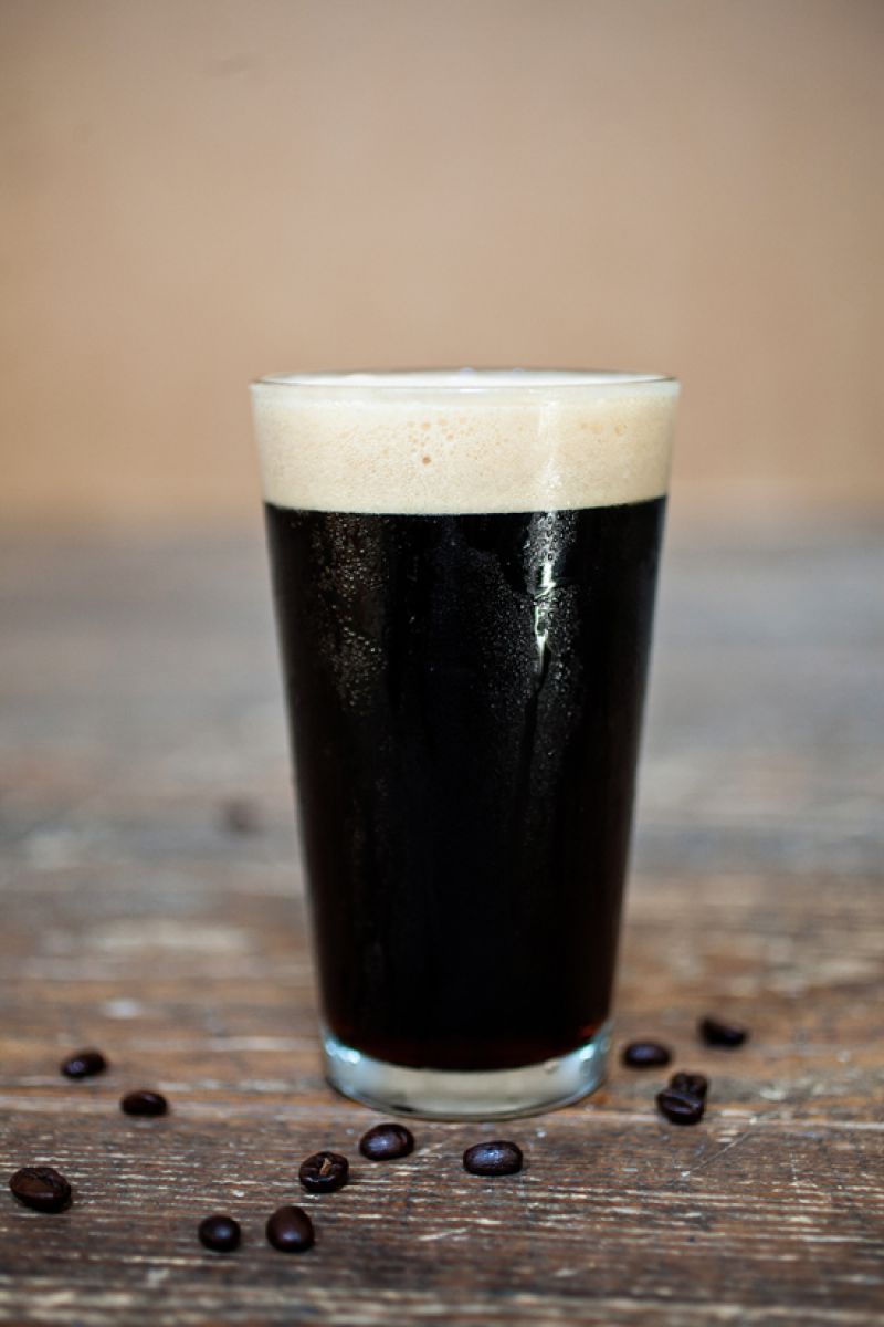 A Pint of Espresso Porter sits amongst coffee beans fromCharleston Coffee Roasters