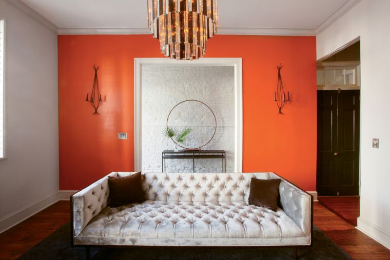 A bold accent wall In Benjamin Moore’s “Fire Dance” enlivens the living room .