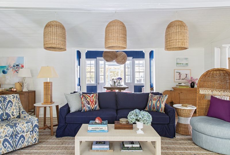 Casual Charms: For the living area, Isbell created three spaces in the former dining room. Serena &amp; Lily wicker pendants and a slip-covered sofa delineate the main seating area, capped by a vintage hooded wicker chair from Chairish.
