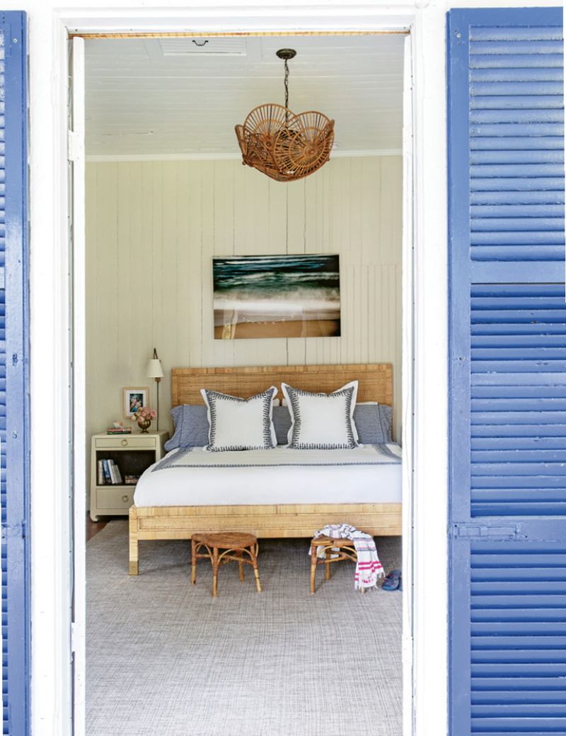 A large Dash and Albert rug softens the master bedroom, which has its own access to the porch. Two vintage rattan stools provide the perfect spot to drop the towels post-beach day, and a pair of Bungalow 5 bedside tables are the ideal place to stash summer reading.