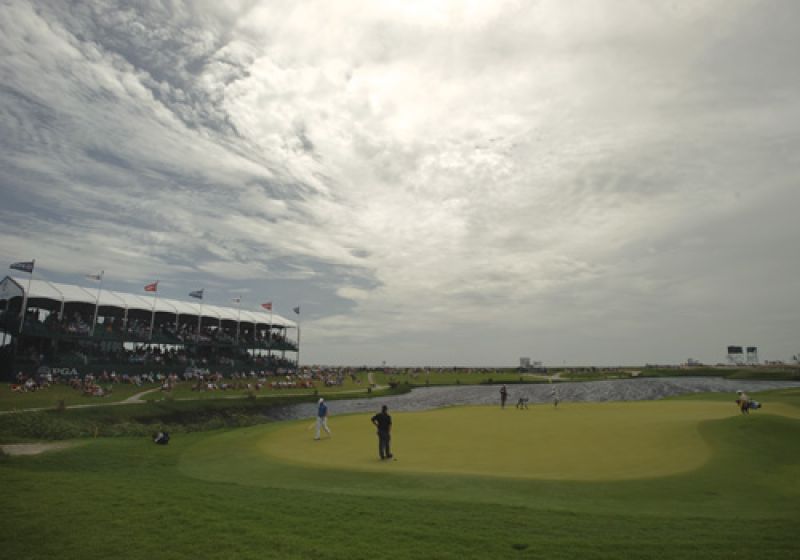 Fans surrounding the 17th green under an ominous sky.