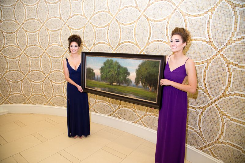 Models showed off a painting up for auction by featured artist Christopher Groves
