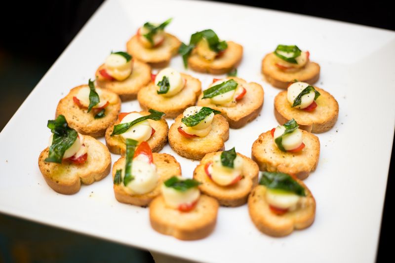 Caprese assemble on artisan crostini, topped with fired basil leaf
