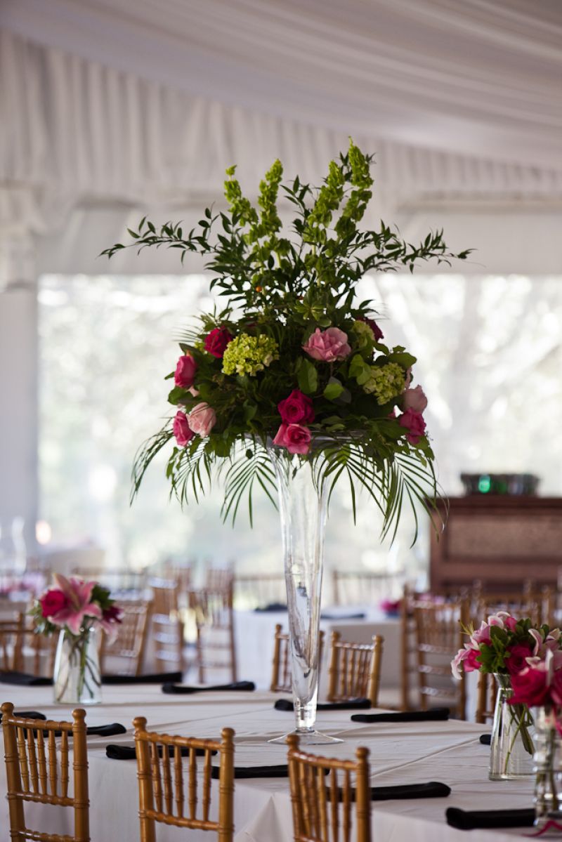 IN BLOOM: Tiger Lily Florist created centerpieces of bright pink roses, lime hydrangea, and green fern. The larger arrangements were elevated, keeping the table conversation-friendly.