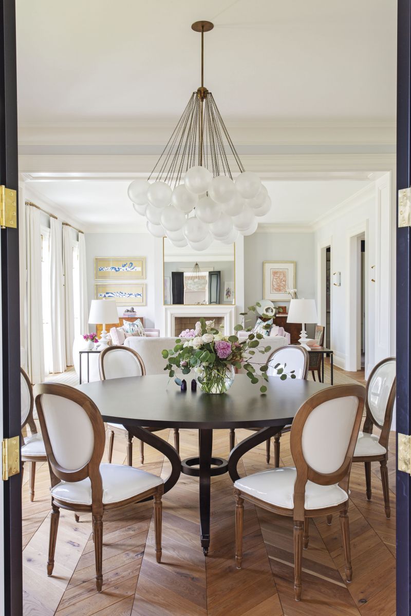 CURVES AHEAD: In the open-plan, formal dining room, curvilinear pieces, such as the Apparatus Studio “Cloud” chandelier from Fritz Porter, Brooks Custom Woodworks table, and Lee Industries chairs, help continue the flow through the rooms.
