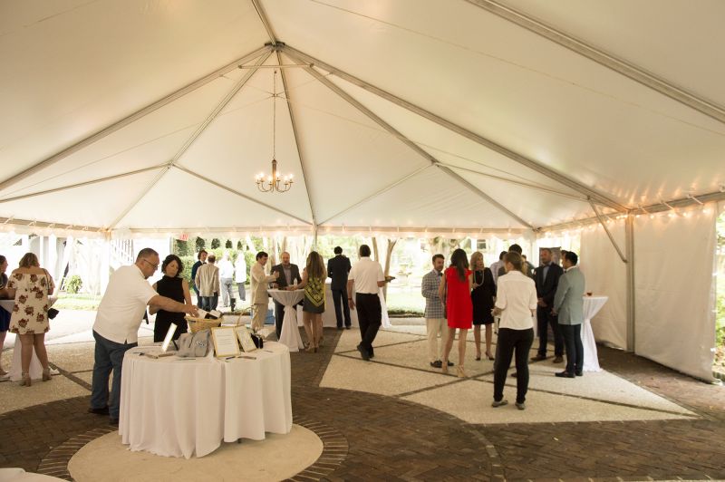 Guests mingled amid bidding tables, music, food, and beverages beneath the main tent.