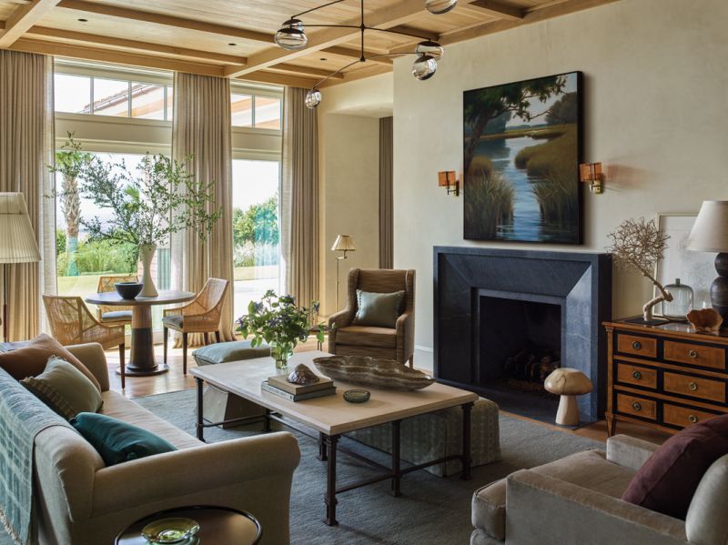 The custom sofa clad in a herringbone linen, Formations limestone and iron coffee table, and soapstone fireplace surround combine natural materials with a muted color palette.