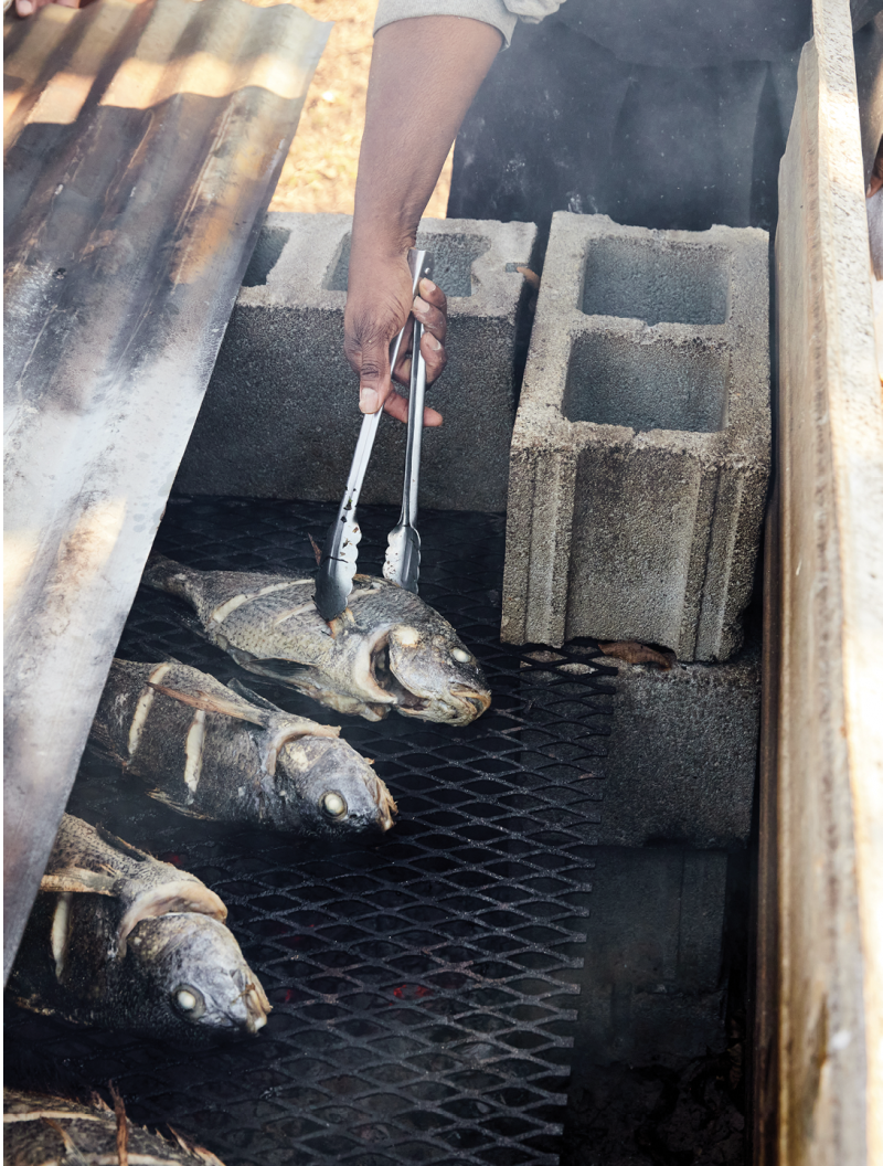 Flipping black bass on the cinder-block oven in preparation for the family supper.