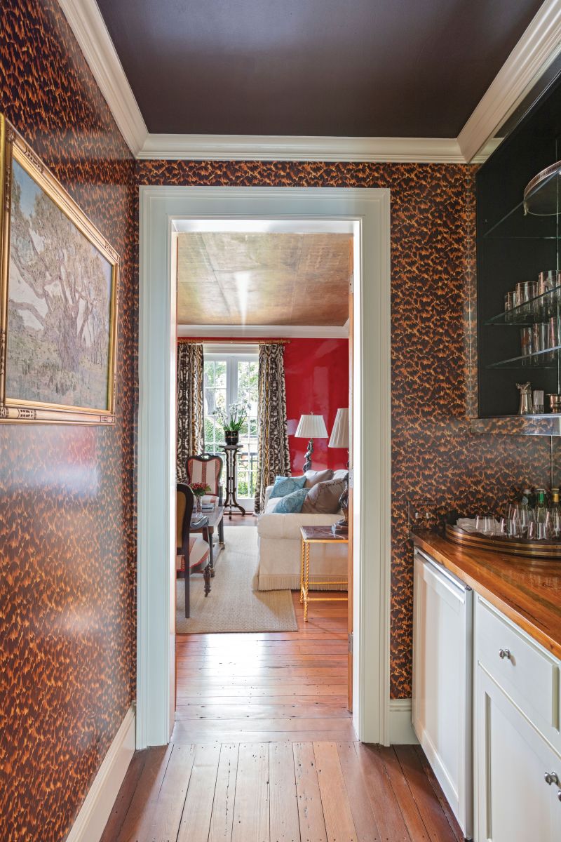 Vintage Zuber wallpaper mounted as a screen breaks up the expanse of red on the far side of the room. The Schumacher “Tortoise” wallpaper in the adjoining wet bar plays well with the gold-leaf ceiling.