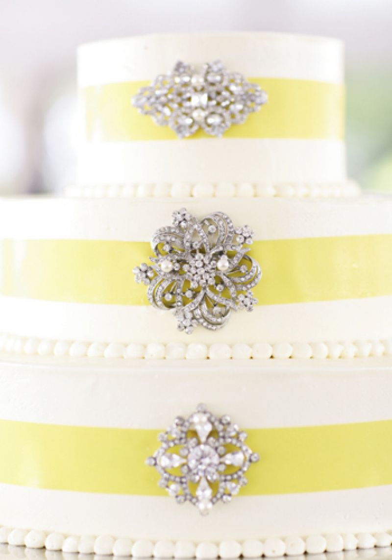 SPARKLY SWEET: With its ribbon and vintage broaches, the three-tiered cake by Fish Restaurant played off the soft yellow of the bride’s bouquet and the ornate crystal detail of her belted gown.