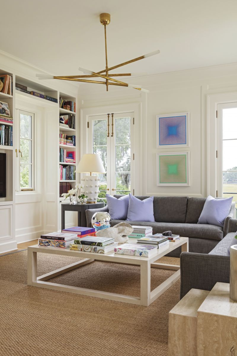 ON THE BRIGHT SIDE: In the family room, a gray Perennials fabric covers the Lee Industries sofa, while pops of purple from the Lee Jofa fabric-covered pillows and art by Leigh Suggs add interest.
