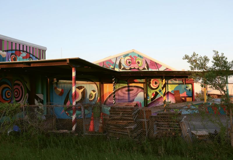 The PlayHouse by Patch Whisky  2015  Spoleto Festival Scene Shop  (1553 King St. Ext.)  When Spoleto festival USA renovated its plain corrugated metal workshop, the powers that be made the apt decision to hire the local artist and muralist to make the exterior “a magnificently muraled piece of art.” visible from I-26, it’s covered in Whisky’s brilliant and comical “rainbow monsters,” which can also be found on buildings throughout the area and up and down the east coast.