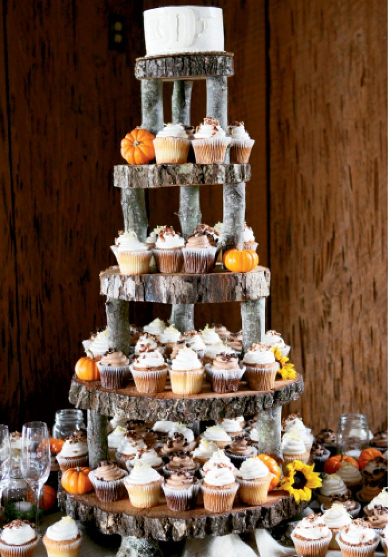 TALL NUMBER: To tie the dessert table to the rest of the wedding, they used a rough-hewn, tiered wooden stand, which Rheney decorated with yellow blooms and tiny orange pumpkins to reiterate the wedding’s palette.