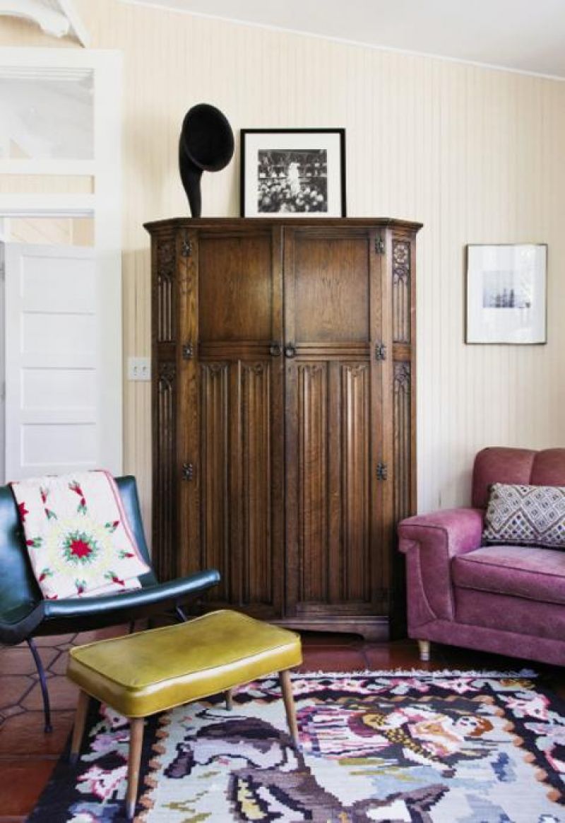 Vivid secondhand seating flanks an early 20th-century French armoire in the sunroom. The rug was made in Turkmenistan in 1957.