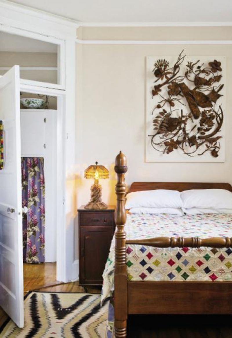 bedside manor: In the master bedroom, an acorn four-poster bed and Hamilton chest of drawers, both handed down through Mark’s family, pair with a sculptural piece by Folly Beach artist Joe Walters.