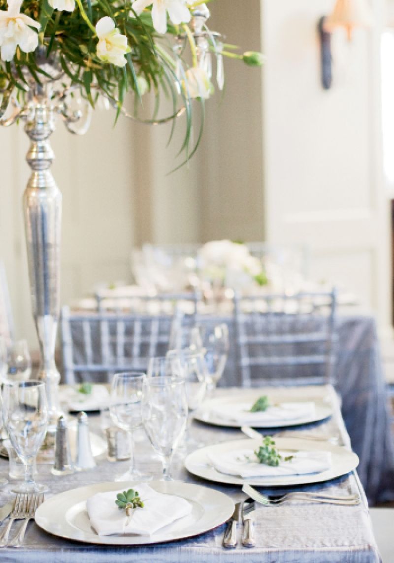 SILVER SETTING: Custom-made silver linens, silver candelabras, silver chargers, and a sea of icy crystal were offset by white French tulips, green bear grass, and posies of Dusty Miller winter berries at each place setting.