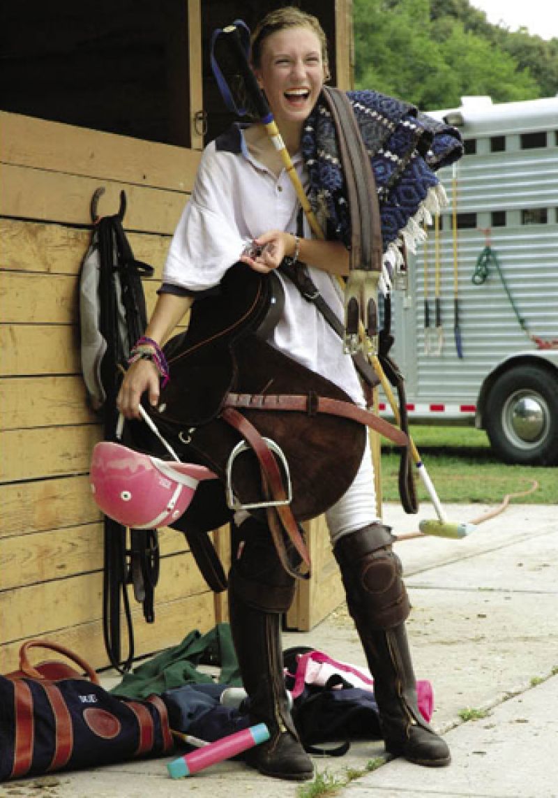 Eliza Limehouse, 14 years old and a fan of the color pink, carries her tack for a spring scrimmage game. She wears leather kneepads for protection and over-chaps to save her boots from wear. She’s a dedicated player, as evidenced by the tiny polo horse illustration on her retainer.