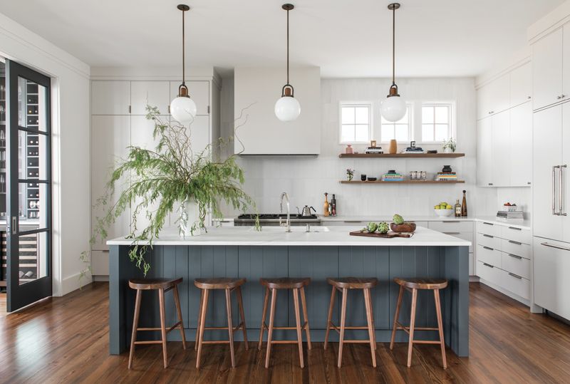 Chill Space: A selection of soft white paints (walls are Benjamin Moore “Chantilly Lace,” cabinets, Farrow &amp; Ball “Ammonite”), combined with warm woods, bronze accents, and a pop of color courtesy of the island, create a sense of coziness in this open-plan kitchen.