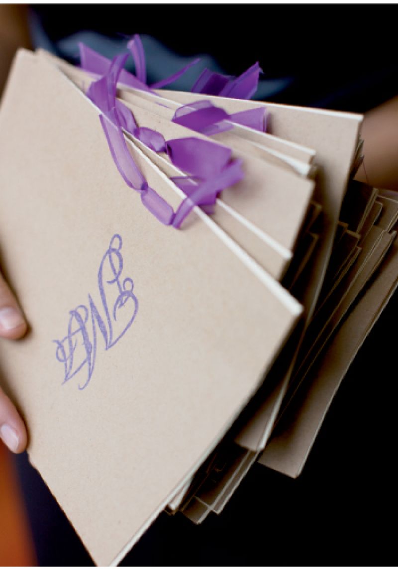 TO THE LETTER: Butcher paper-colored programs emblazoned with violet monograms echoed the location’s palette and one of the wedding’s sassy shades.