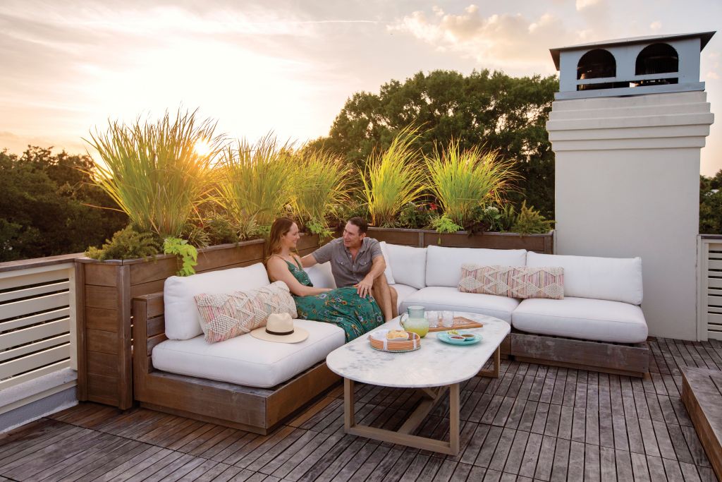 <strong>Happy Hours</strong> - Erin and Robert Spencer relax in their rooftop lounge area, one of two must-haves when the couple decided to build a new home on their property near the Pitt Street Bridge. It’s a primo spot for toasting the sunset, especially when Spence is making his signature margaritas. <strong>Location:</strong> Mount Pleasant <strong>Issue:</strong> October 2020,  “Higher Ground” <strong>Photographer:</strong> Margaret Wright <a href="https://charlestonmag.com/features/higher_ground_a_bachelor_pad_makes_way_for_a_newlywed_nest_complete_with_a_rooftop_deck"><strong>&gt;&gt;CLICK HERE TO READ THE ARTICLE</strong></a>